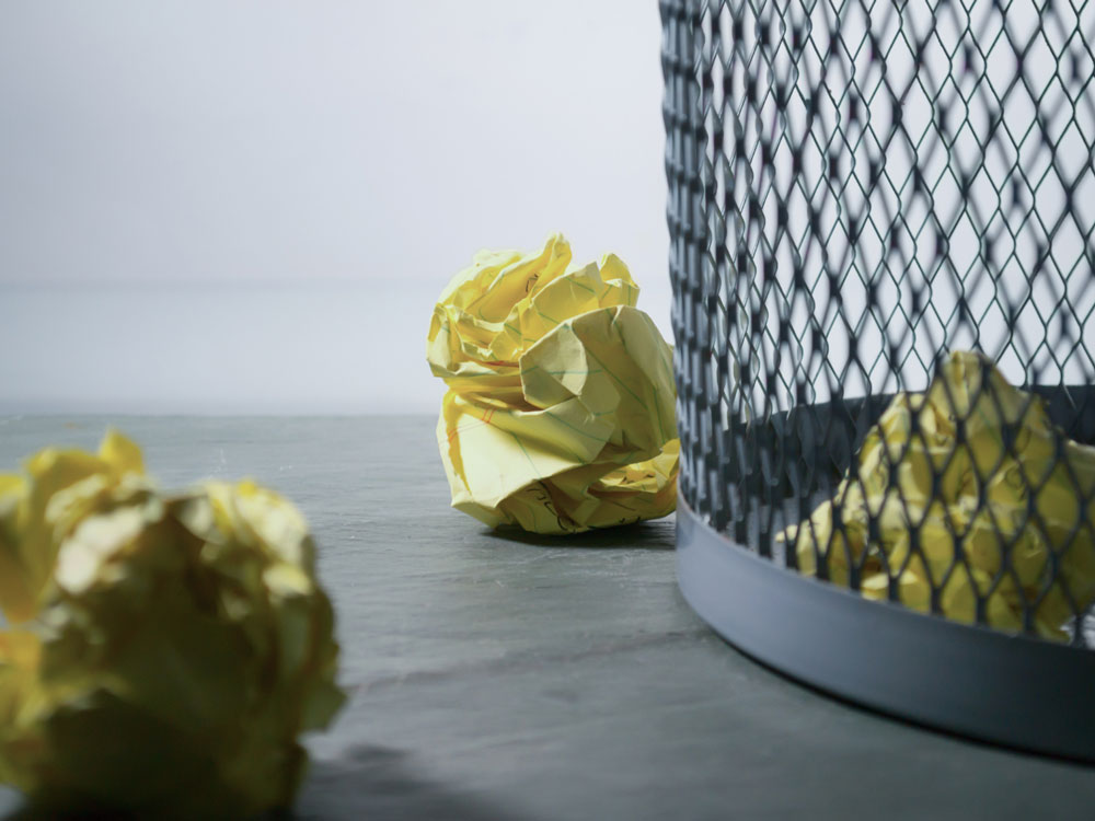 Crumpled pieces of paper by a trash can
